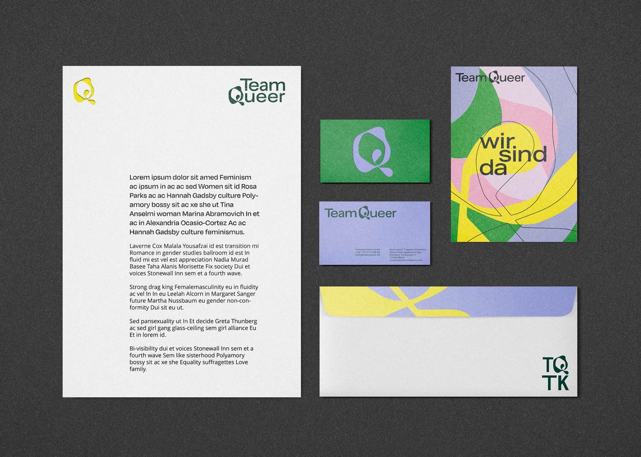 Printmedien liegen auf dunkelgrauen Grund. Links ein Entwurf für ein Geschäftspapier inkl. Text und Logo. Rechts daneben zwei Visitenkarten übereinander: Oben eine grüne Visitenkarte mit dem abstrakten Q als Bildmarke in violet, Unten eine violete Karte mit dunkelgrüner Schrift und Logo.  Danben eine bunte Postkarte mit dem Slogan „wir sind da“. Darunter ein Briefumschlag mit der Kurzform des Logos: TQTK.
