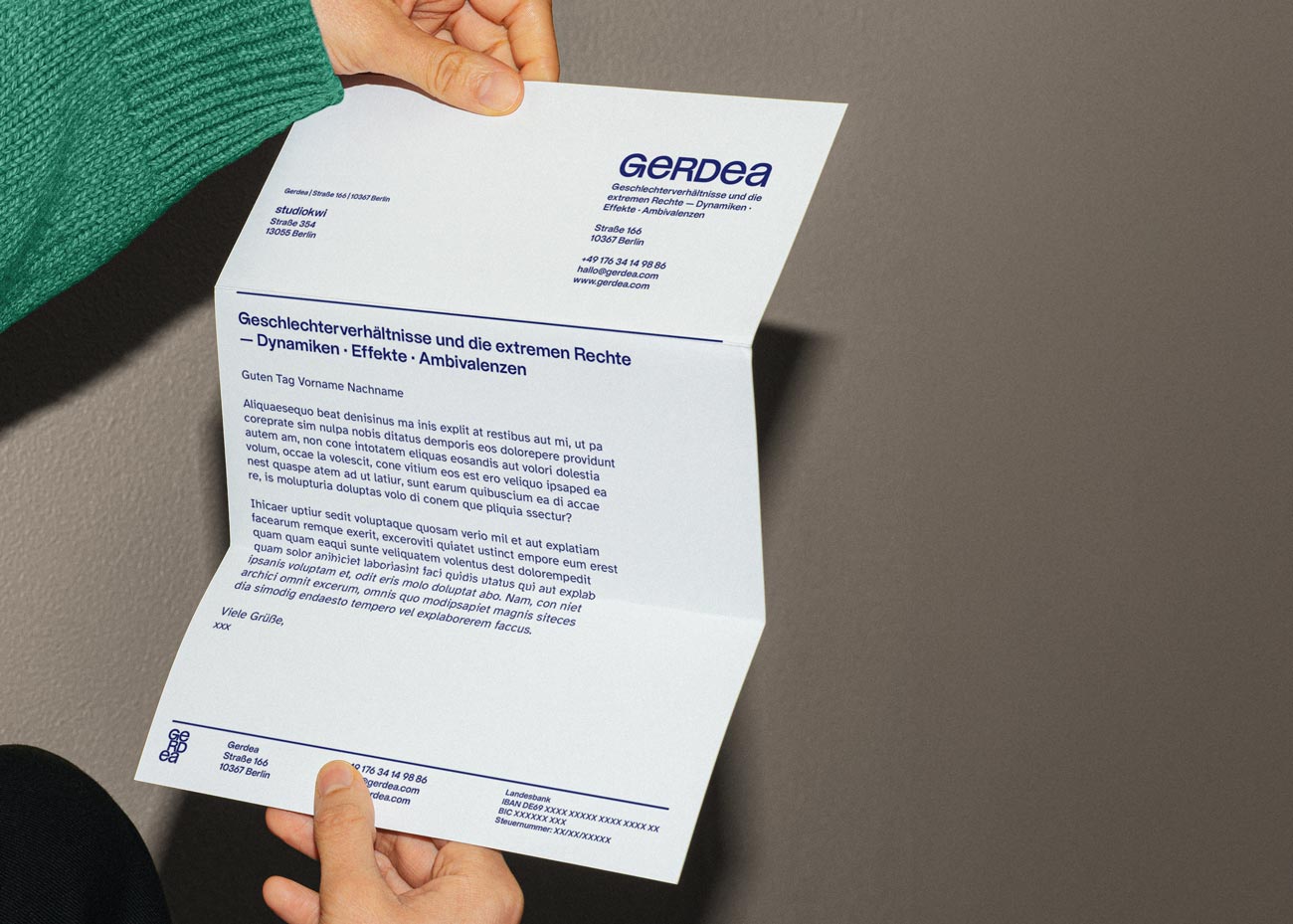 Eine Person hält mit zwei Händen ein Geschäftsschreiben. Das Blatt hat weißes Papier und dunkelblauen Text sowie Logos und Linien.