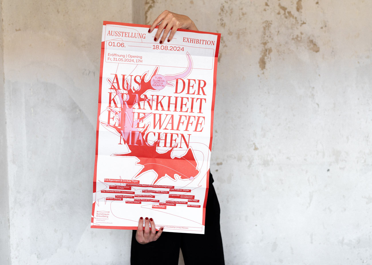 Das Poster wird von einer Person die nicht sichtbar ist vor einer grauen gesprenkelten Wand gehalten. Lediglich die schwarze Hose und die Hände sind im Bild. Das Poster zeitg eine rote, abstrakte und spitze Form. Darüber der Titel Aus der Krankheit eine Waffe machen. Darunter die Namen der Künstler*innen sowie rote Linien.