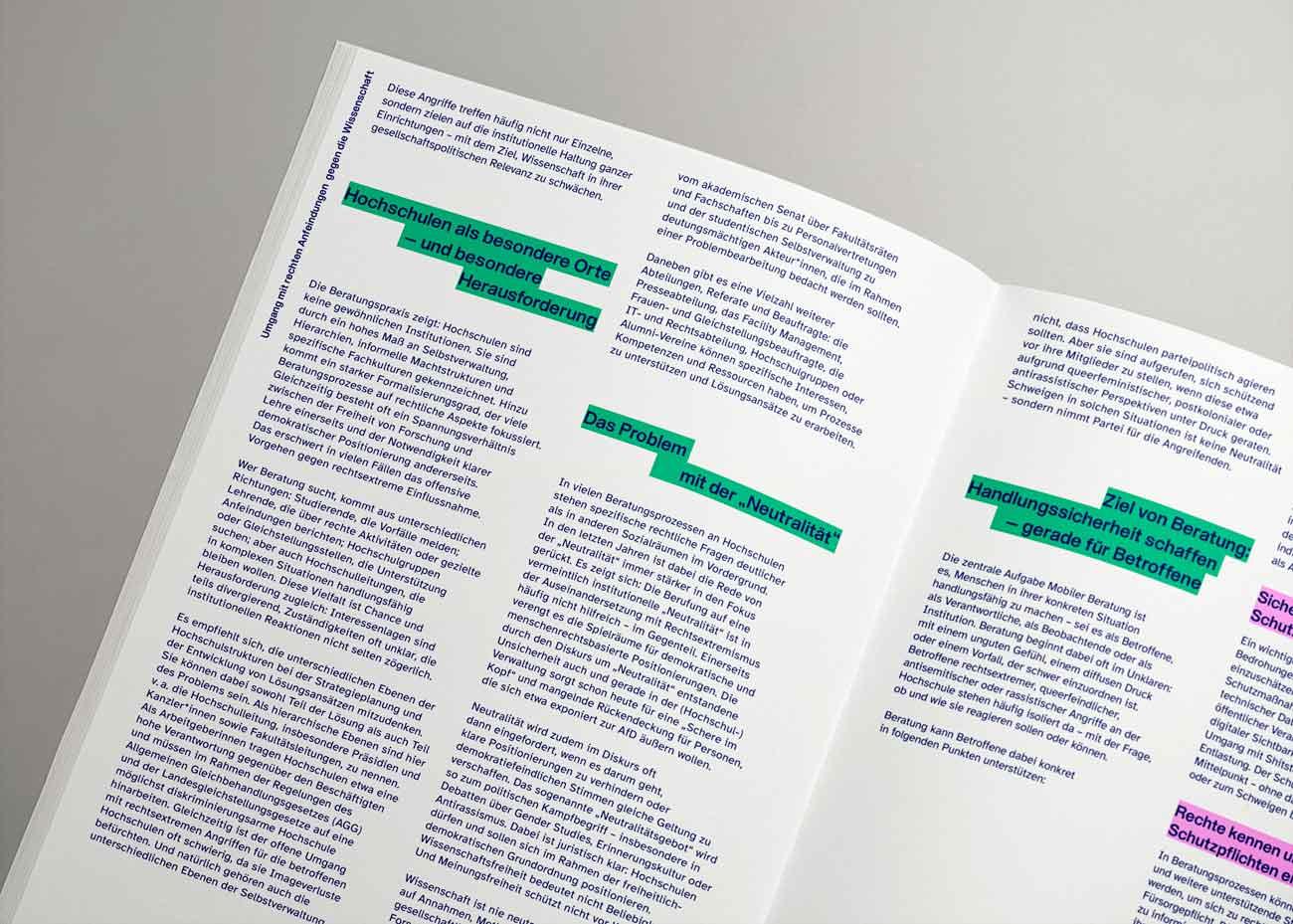 Detailaufnahme einer aufgeschlagenen Publikation mit mehrspaltigem Text in dunkelblauer Schrift auf weißem Hintergrund. Überschriften sind mit grünen Rechtecken hinterlegt. Die Seiten sind sauber und klar gestaltet, mit einem modernen Layout, das Absätze und Überschriften deutlich voneinander trennt. Die Publikation liegt auf einer hellgrauen Oberfläche.