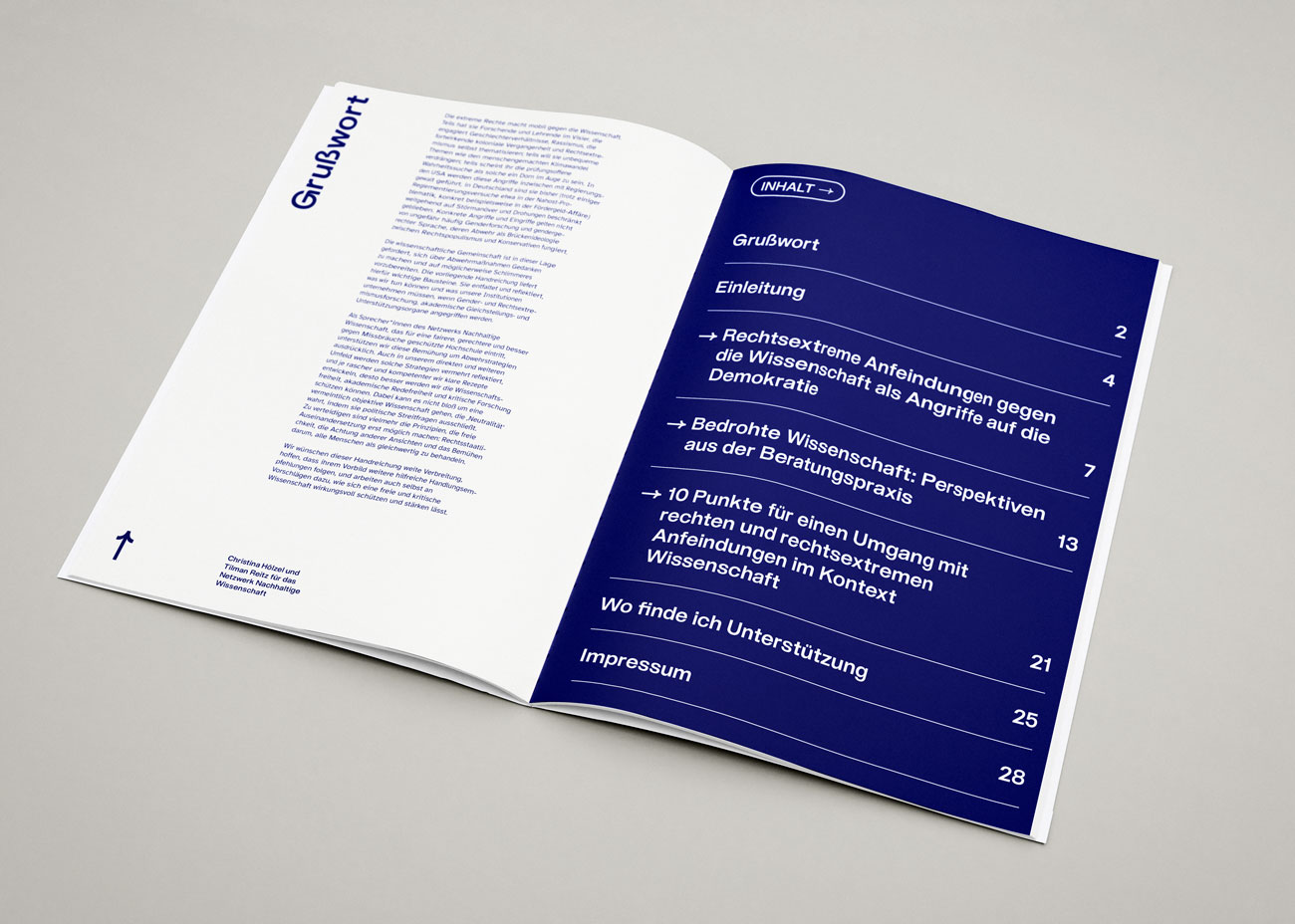 Eine aufgeschlagene Publikation mit einem weißen linken und einem dunkelblauen rechten Blatt. Das linke Blatt trägt den blauen Titel »Grußwort« und darunter einen Fließtext. Das rechte Blatt zeigt ein Inhaltsverzeichnis mit weißer Schrift auf dunkelblauem Hintergrund. Die Kapitelüberschriften sind nummeriert und teilweise mit Pfeilen markiert. Am unteren linken Rand des linken Blattes befindet sich ein kleiner blauer Pfeil nach oben. Die Gestaltung ist klar und modern mit serifenloser Schrift.