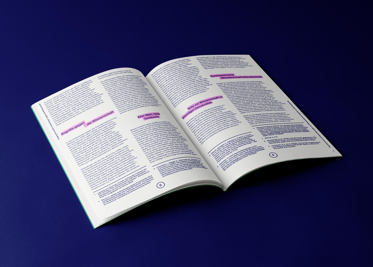 Eine aufgeschlagene Publikation mit mehrspaltigem Text und mehreren pink hinterlegten Hervorhebungen auf dunkelblauem Untergrund.